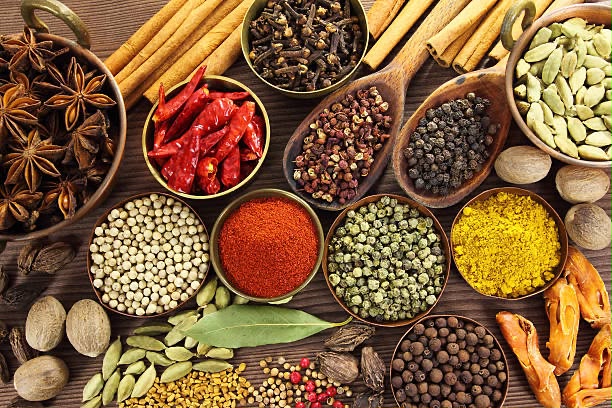 Indian whole and ground spices in brass bowls and wooden spoons